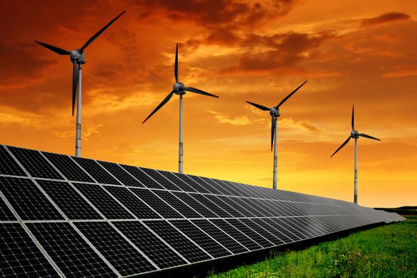 Wind turbines and solar panels at sunset